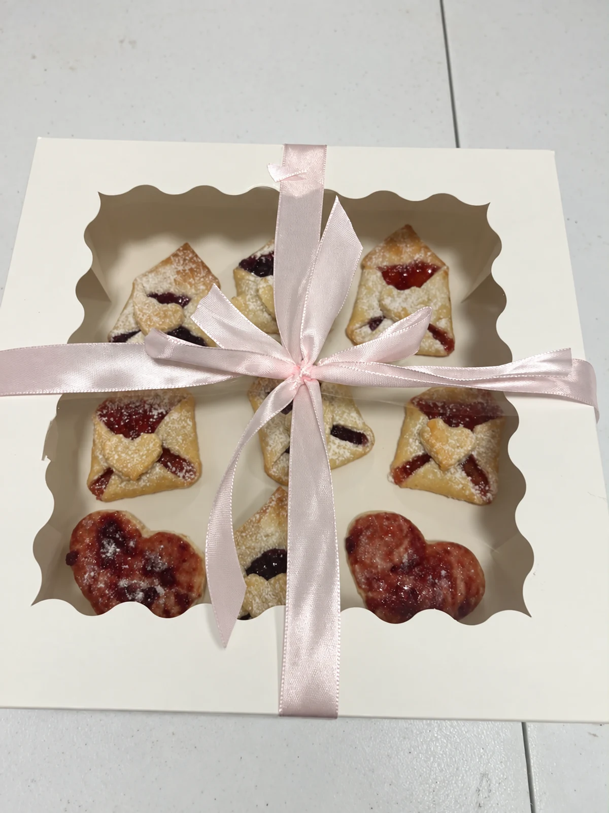 Pastries in a cream window box tied with a pale pink ribbon