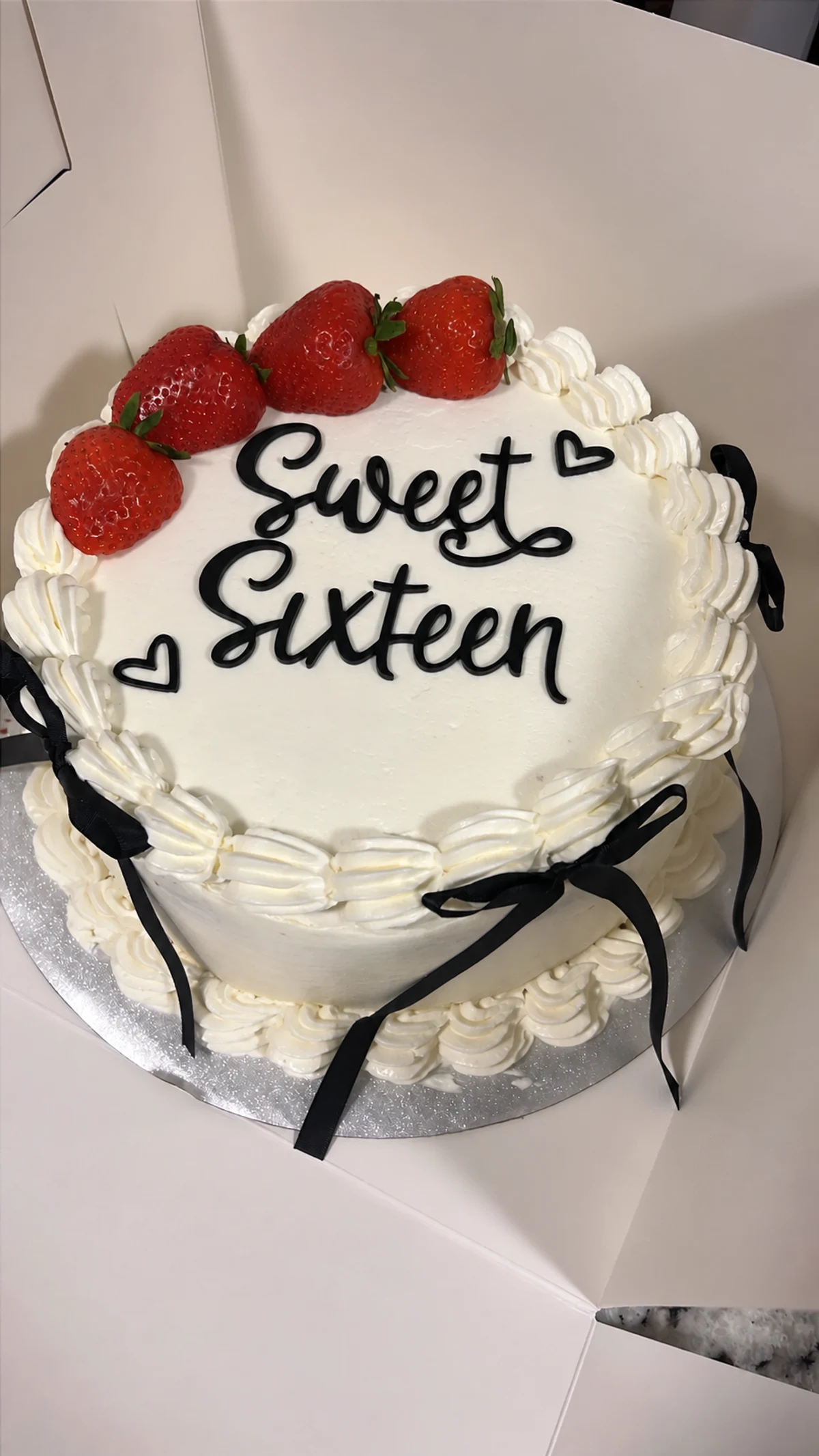 Cream Sweet Sixteen cake with strawberries and black bows